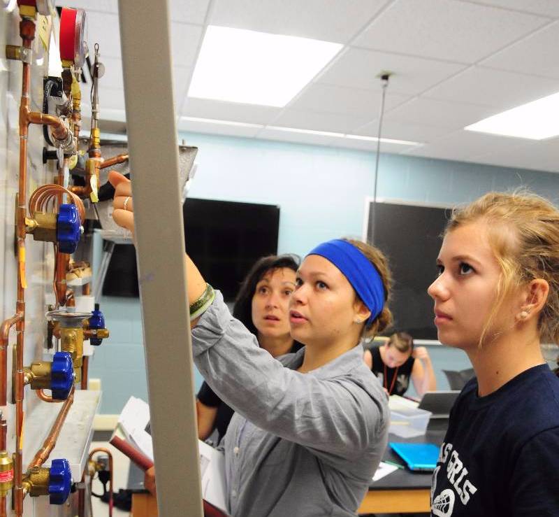 Students take measurements on a refrigeration laboratory demonstration in the introduction to engineering lab