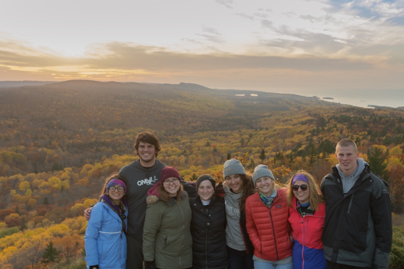 students on mountain with forest below in fall colors