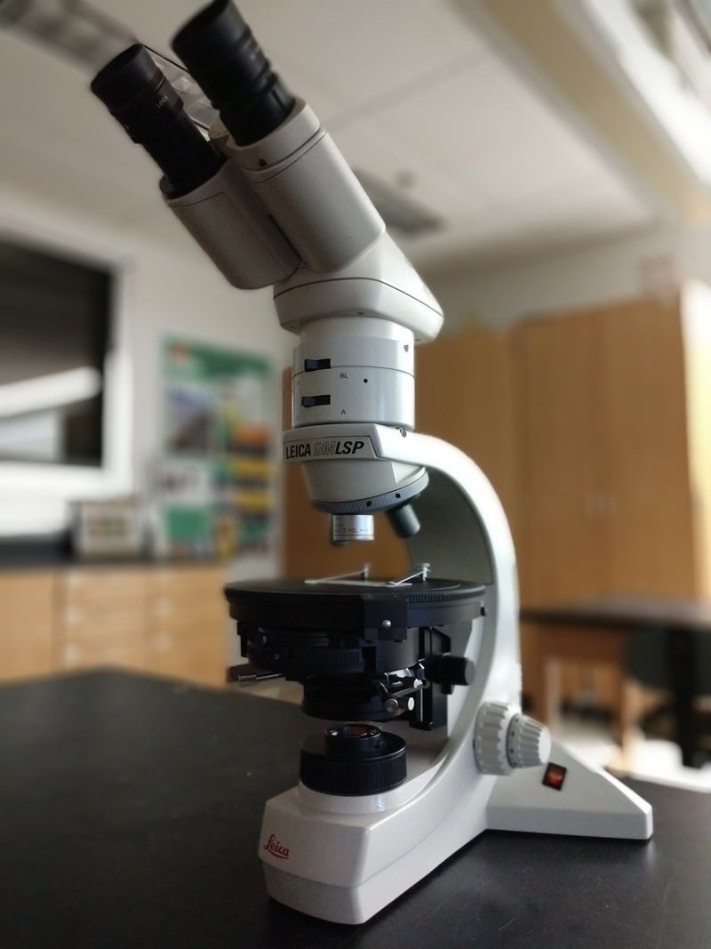 a binocular petrographic microscope on a lab table